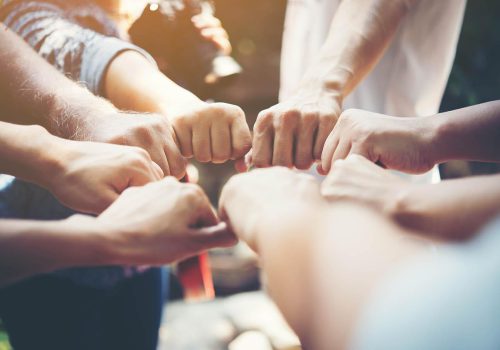 Close up of young people putting their hands together. Team with stack of hands showing unity and teamwork.